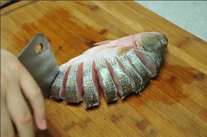 將鱸魚清洗干凈，從脊椎處切斷至腹部，腹部保留1cm左右不要切斷。