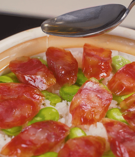 大米出現(xiàn)小孔時(shí)開(kāi)蓋放香腸，往鍋邊淋入少許油，再燜煮8~10分鐘左右。