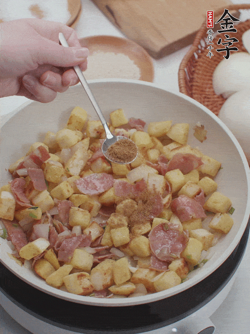 起鍋少油，煸香洋蔥丁、蔥白，加入金字培根火腿翻炒幾下，再加入饅頭丁、1小勺孜然粉、少許鹽翻炒均勻并鋪平。