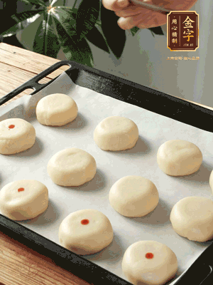 收口向下放在案板上，輕輕將月餅坯按扁，用筷子點紅點做裝飾