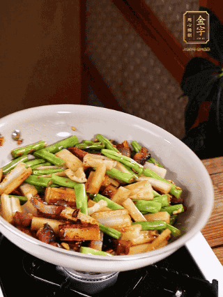 油熱下蒜末、干辣椒、醬肉煸炒出香味，依次下藕條、豆角翻炒均勻